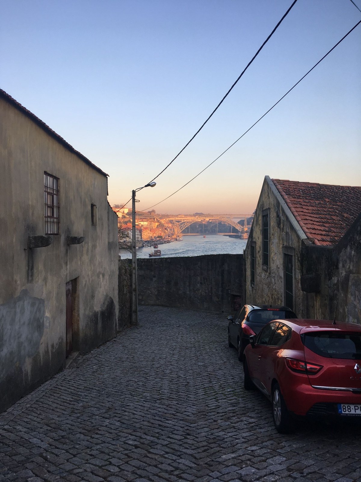 Descending cobbled street with a bridge view in Porto