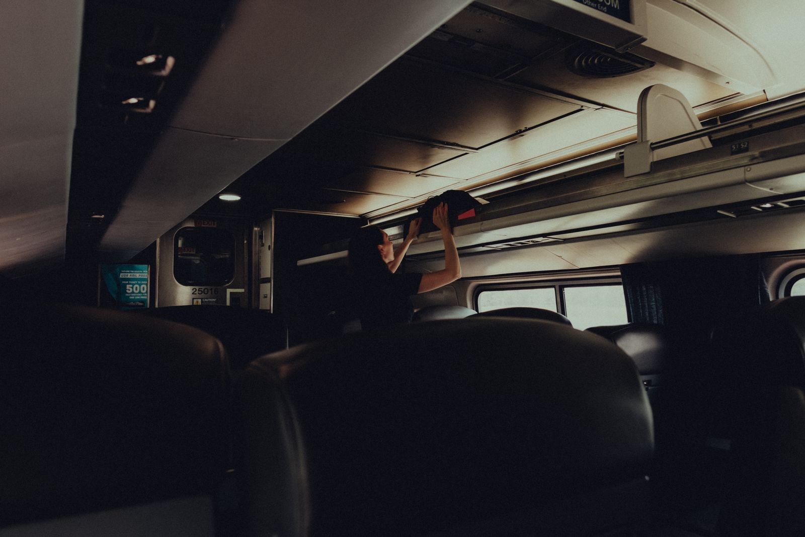 Traveler lifting a bag onto an overhead train luggage rack
