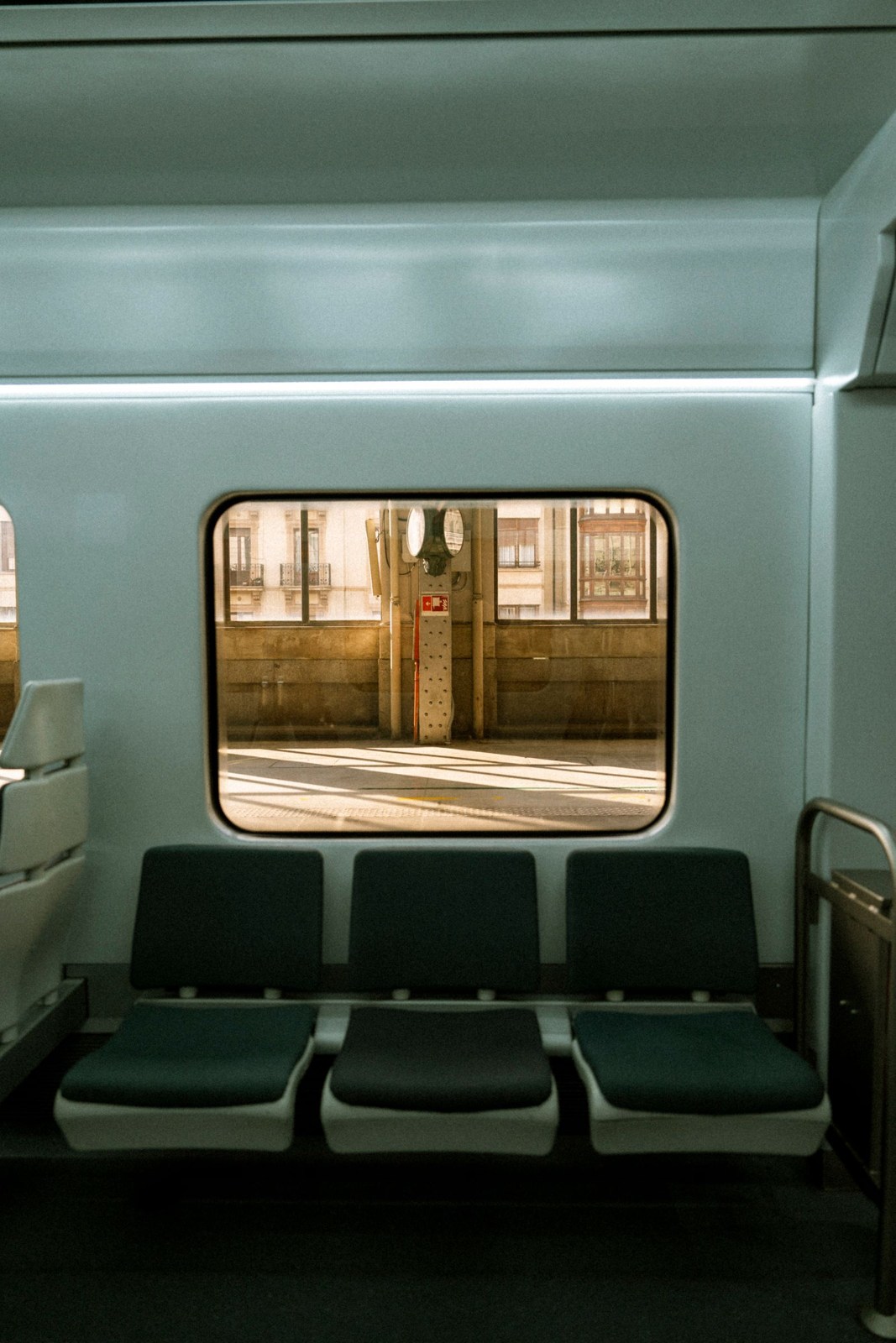 Empty train seats beside a window overlooking the platform