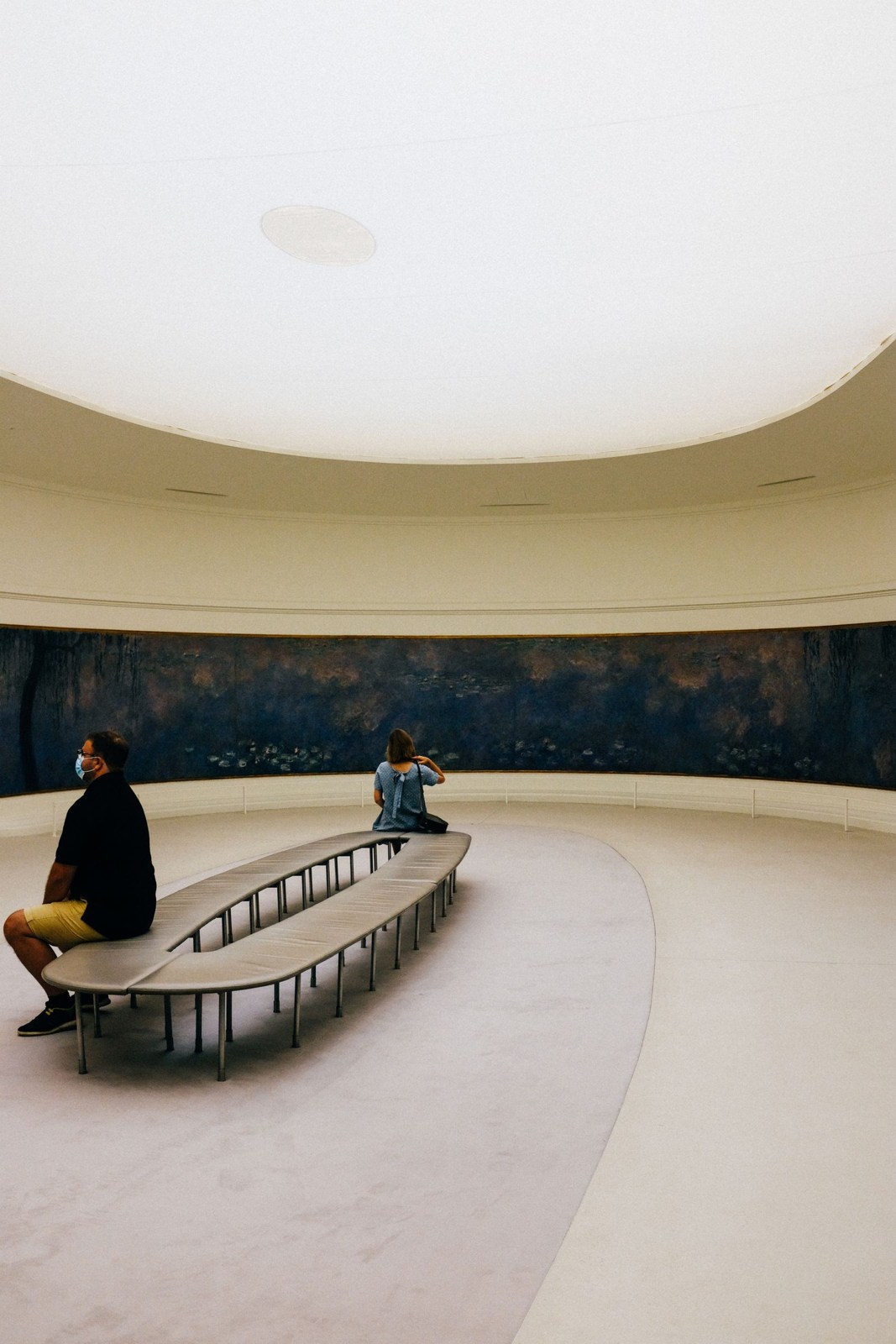 Visitors on a bench inside a museum gallery